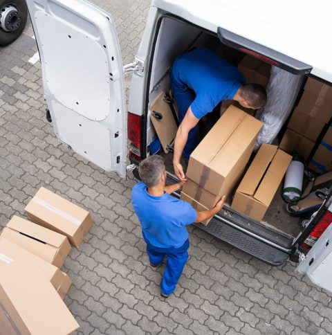 2 men loading a van with cardboard boxes full of items from a house clearance